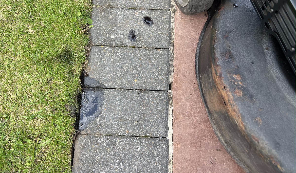 oil spilled out of lawn mower exhaust onto patio slabs and grass