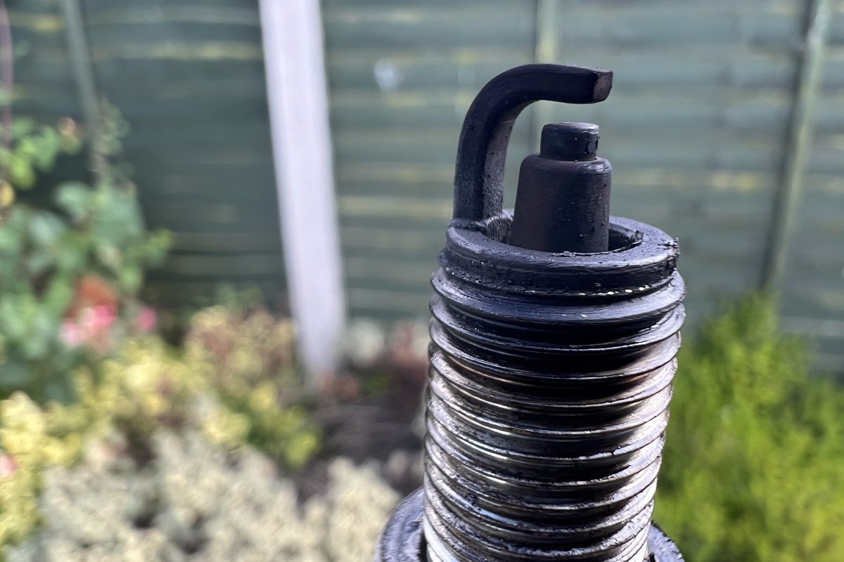 dirty lawn mower spark plug that has carbon buildup and is causing starting issues