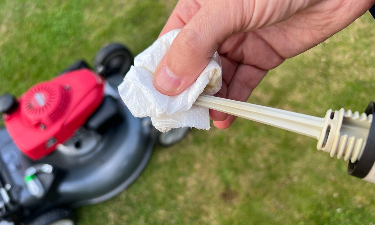 wiping lawn mower oil dipstick clean to get an accurate reading of oil level